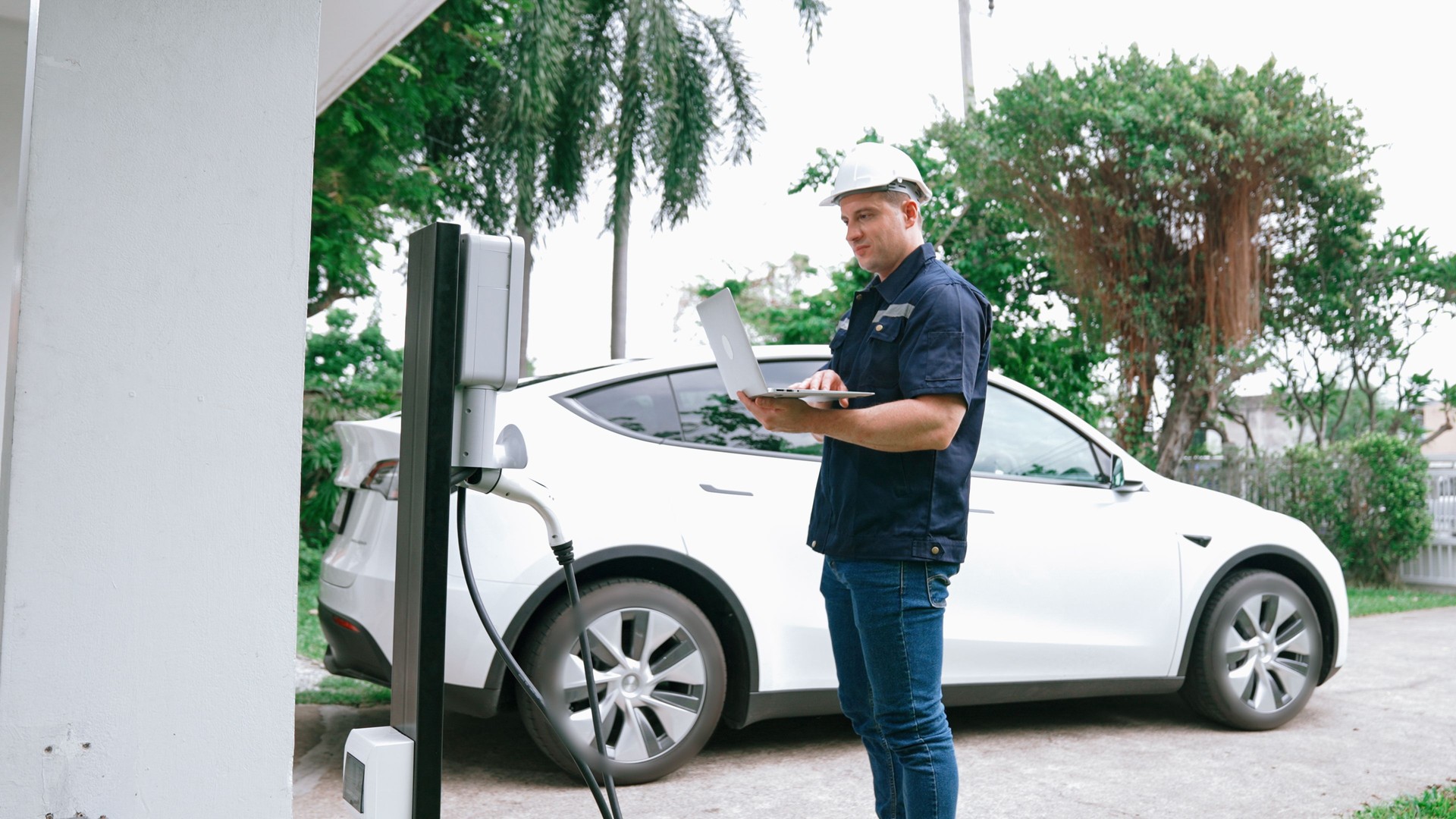 Qualified technician working with laptop for home EV station. Synchronos